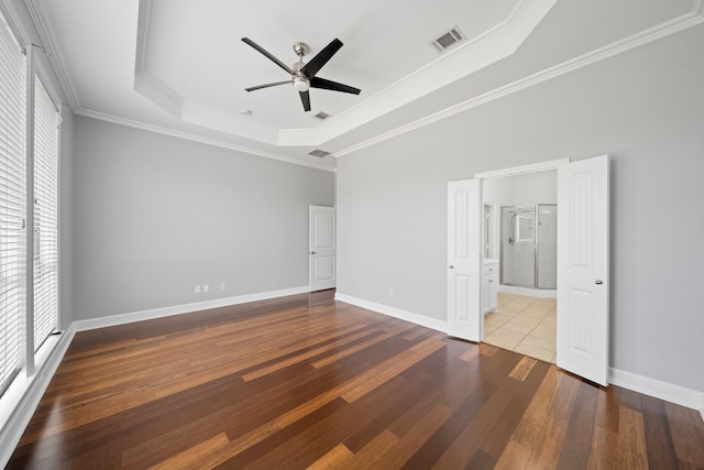 unfurnished bedroom featuring crown molding, tile patterned floors, a raised ceiling, ceiling fan, and connected bathroom