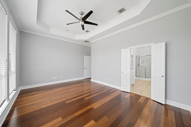 unfurnished bedroom with hardwood / wood-style floors, a raised ceiling, visible vents, and crown molding