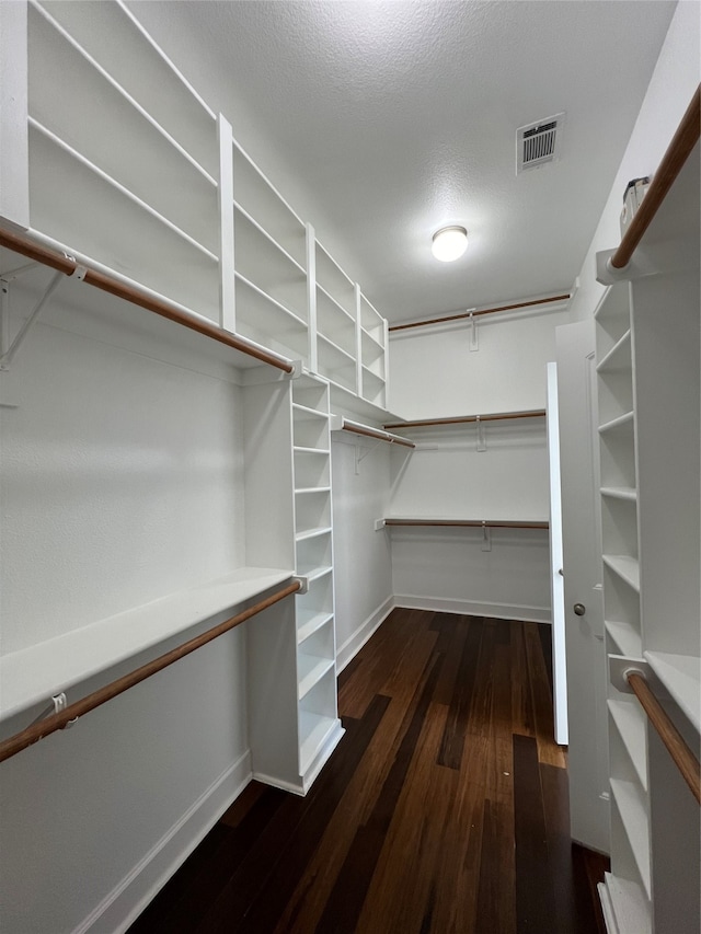 walk in closet with dark wood-type flooring