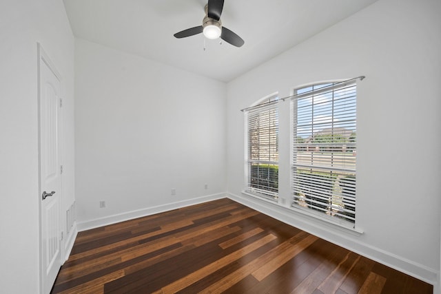 spare room with dark wood-style floors, a ceiling fan, and baseboards