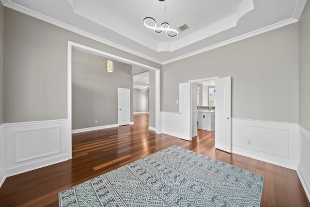 interior space featuring a tray ceiling, hardwood / wood-style flooring, a notable chandelier, and ornamental molding