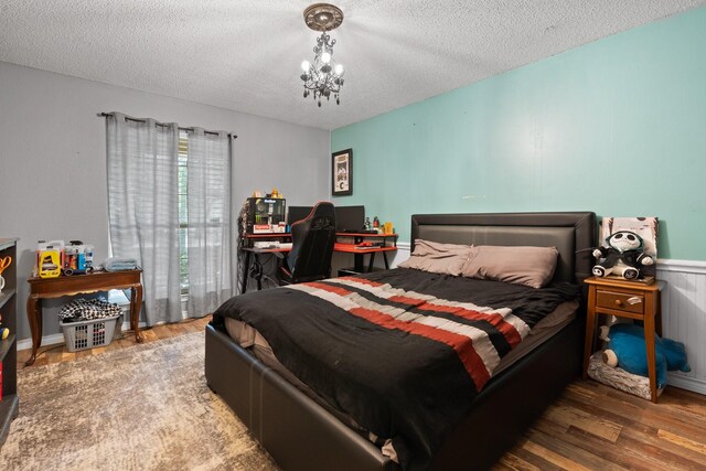 bedroom with a textured ceiling, a chandelier, and hardwood / wood-style flooring