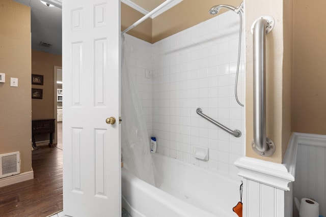 bathroom with wainscoting, visible vents, shower / bath combination with curtain, and wood finished floors