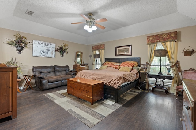 bedroom with ceiling fan, dark hardwood / wood-style flooring, and a tray ceiling