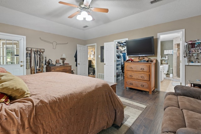 bedroom with ceiling fan, a spacious closet, dark hardwood / wood-style floors, ensuite bathroom, and a textured ceiling