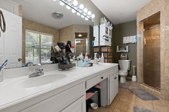 bathroom featuring double sink vanity, tile patterned floors, an enclosed shower, a textured ceiling, and toilet