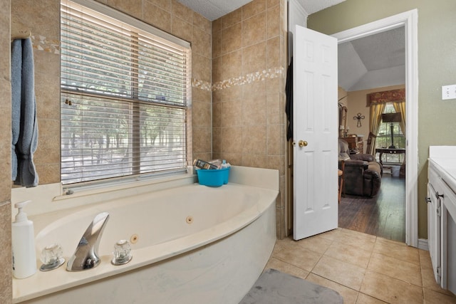 full bath featuring a whirlpool tub, vanity, a textured ceiling, and tile patterned floors