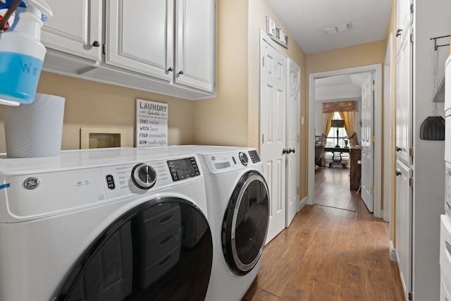 washroom with cabinets, hardwood / wood-style floors, and separate washer and dryer