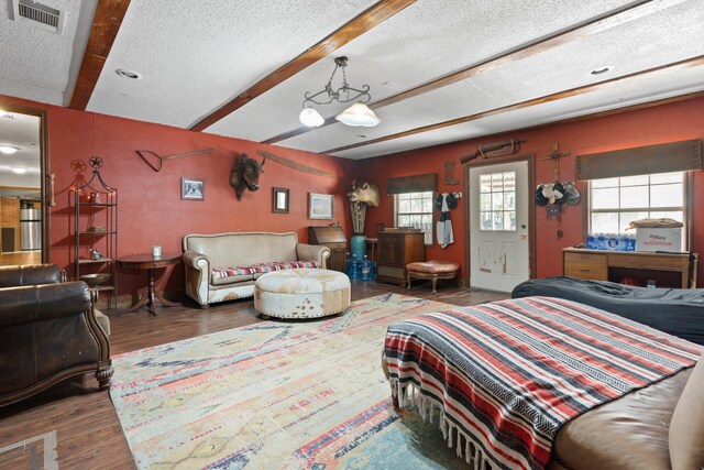 bedroom featuring a textured ceiling, beam ceiling, and hardwood / wood-style flooring