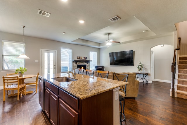 kitchen with a kitchen breakfast bar, a kitchen island with sink, sink, and dark hardwood / wood-style flooring