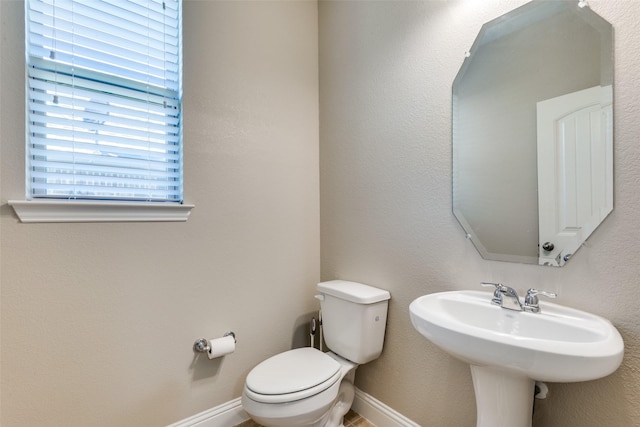 bathroom with toilet, baseboards, and a sink