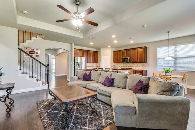 living room with dark hardwood / wood-style floors, a raised ceiling, and ceiling fan