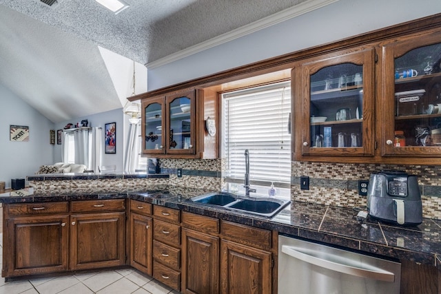 kitchen with dishwasher, sink, vaulted ceiling, a textured ceiling, and light tile patterned flooring