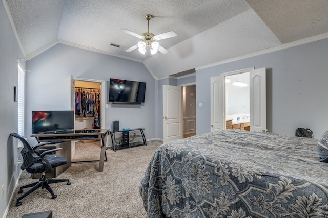 carpeted bedroom with ceiling fan, lofted ceiling, a walk in closet, a closet, and ornamental molding