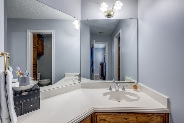 bathroom with vanity, toilet, and a textured ceiling