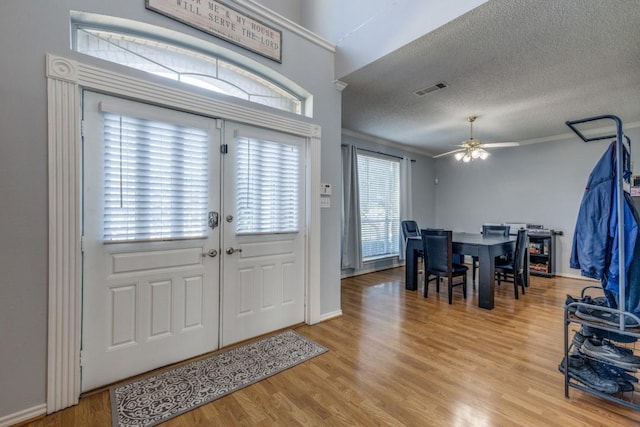 entrance foyer featuring ceiling fan, light hardwood / wood-style floors, a textured ceiling, and ornamental molding