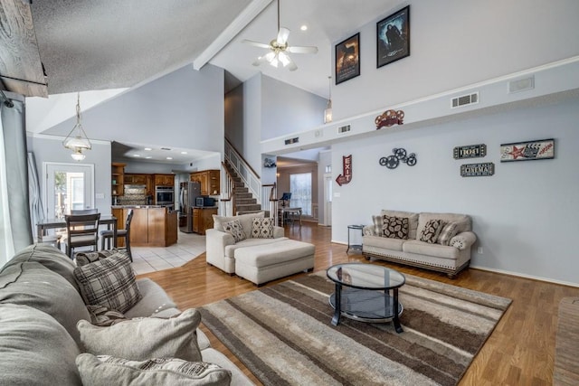 living room with beamed ceiling, ceiling fan, light wood-type flooring, and high vaulted ceiling