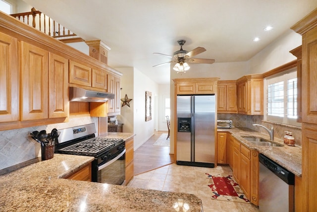 kitchen with sink, light tile patterned floors, appliances with stainless steel finishes, light stone countertops, and decorative backsplash