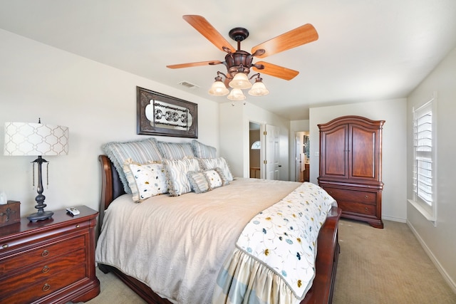 bedroom featuring light carpet, ensuite bath, and ceiling fan