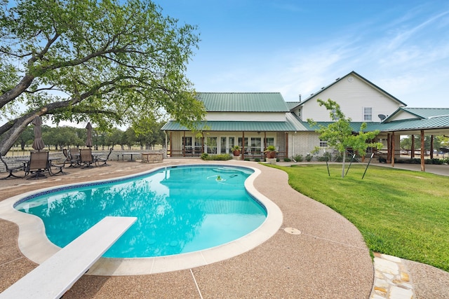 view of swimming pool featuring a yard, a patio area, and a diving board