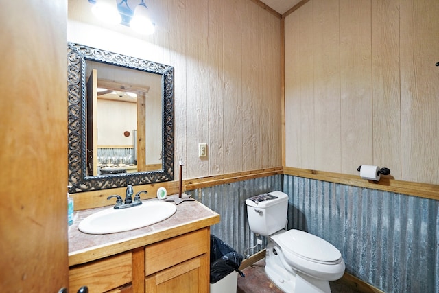 bathroom featuring vanity, toilet, and wood walls