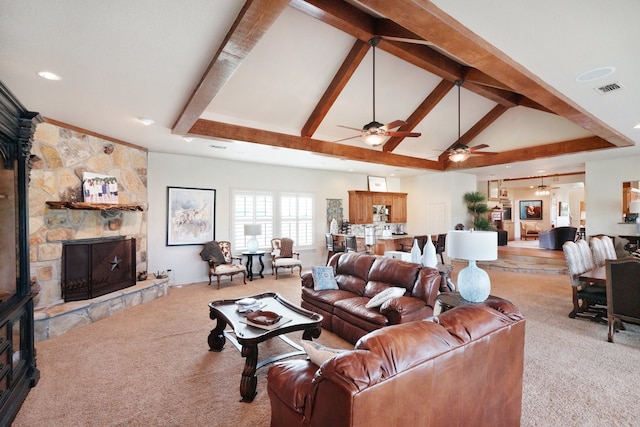 carpeted living room featuring beamed ceiling, ceiling fan, a stone fireplace, and high vaulted ceiling