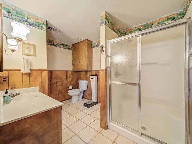 bathroom with a shower with shower door, wood walls, vanity, tile patterned flooring, and toilet