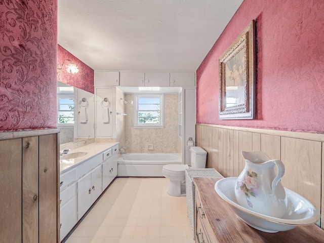 bathroom with a textured ceiling, plenty of natural light, vanity, and toilet