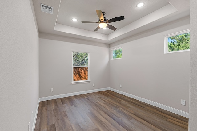 empty room with ceiling fan, hardwood / wood-style floors, and a raised ceiling