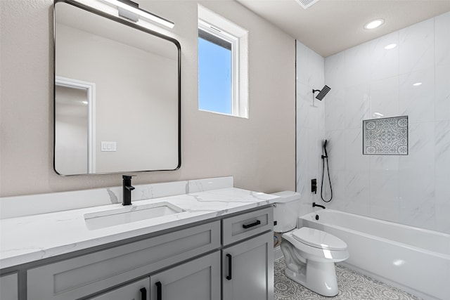 full bathroom featuring tile patterned flooring, tiled shower / bath, vanity, and toilet