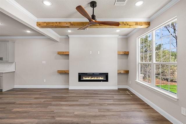 unfurnished living room with ceiling fan, hardwood / wood-style flooring, plenty of natural light, and beamed ceiling