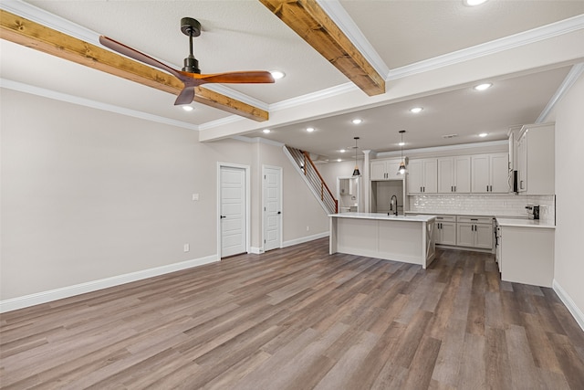 kitchen featuring beam ceiling, hardwood / wood-style flooring, a kitchen island with sink, ceiling fan, and hanging light fixtures