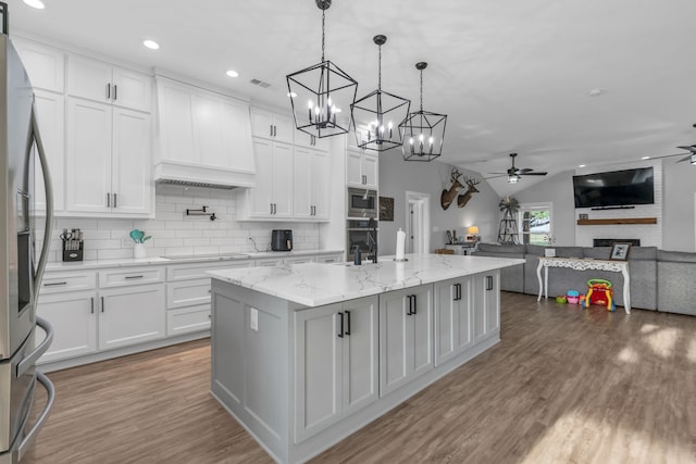 kitchen featuring hardwood / wood-style floors, custom exhaust hood, ceiling fan with notable chandelier, black appliances, and white cabinets