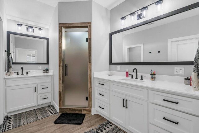 bathroom with an enclosed shower, hardwood / wood-style floors, and double sink vanity