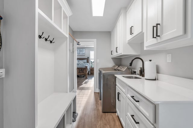 mudroom featuring light wood-type flooring, washer and dryer, and sink