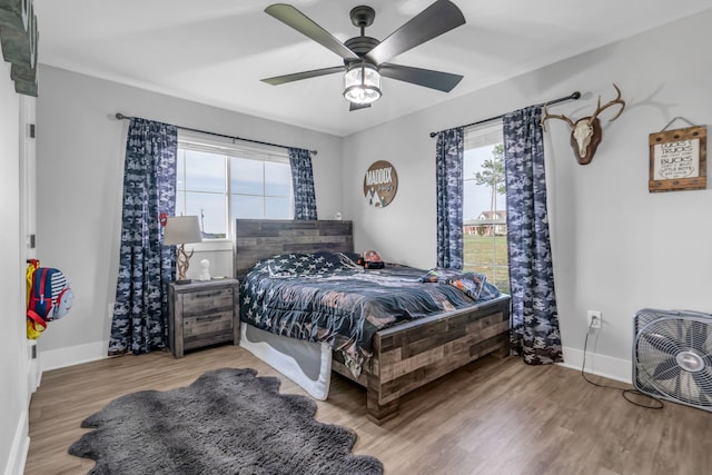 bedroom featuring a ceiling fan, light wood-style flooring, and baseboards