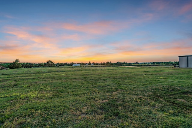 yard at dusk featuring a rural view