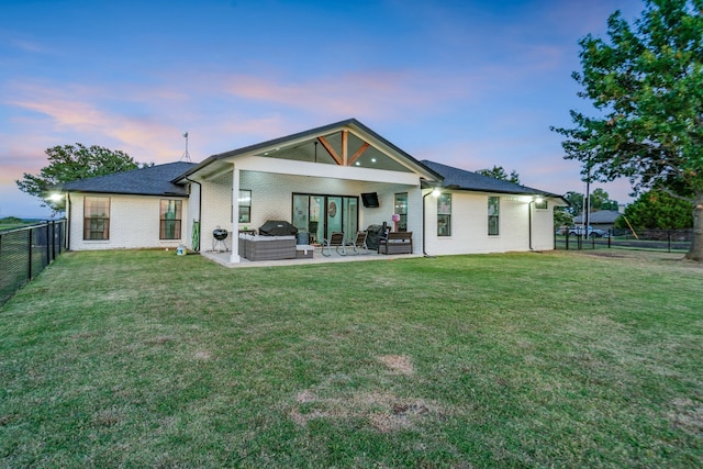 back of property with a patio area, a fenced backyard, an outdoor living space, and a lawn