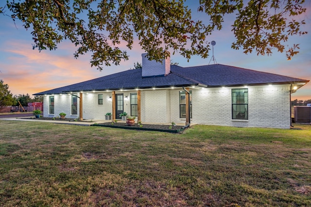 single story home with central AC unit and a yard