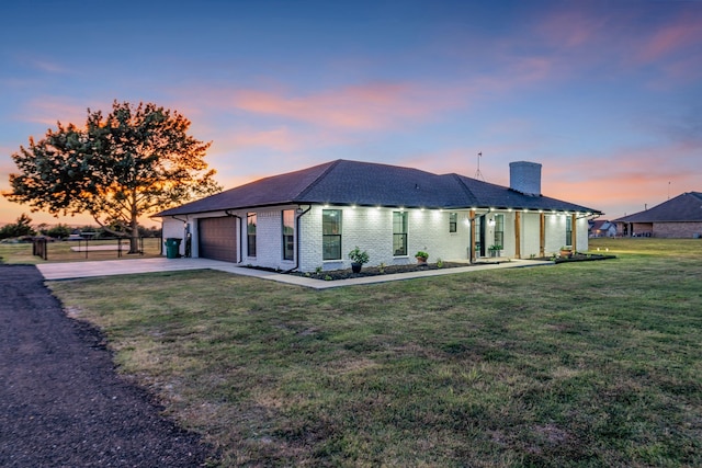 back house at dusk featuring a yard and a garage