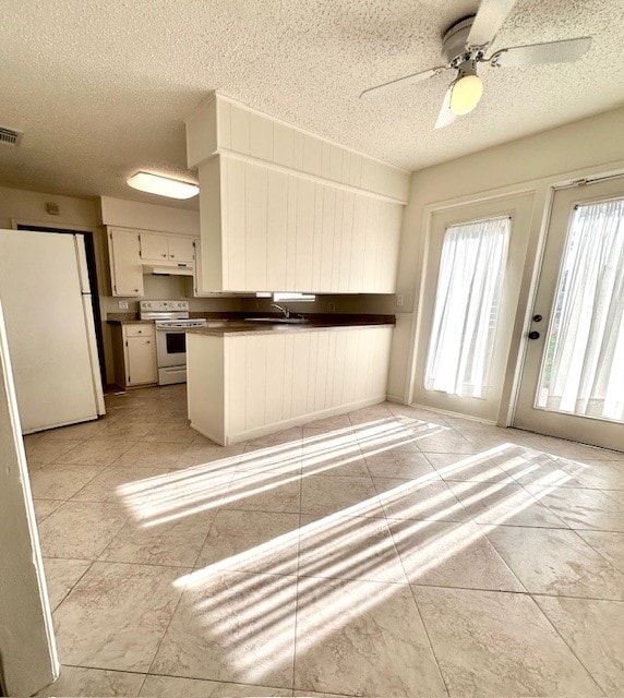 kitchen featuring white appliances, a textured ceiling, kitchen peninsula, white cabinetry, and ceiling fan