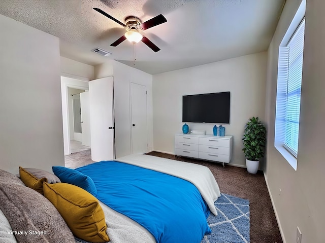 carpeted bedroom with ceiling fan and a textured ceiling