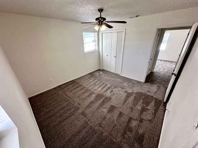 unfurnished bedroom with a closet, carpet floors, a textured ceiling, and ceiling fan