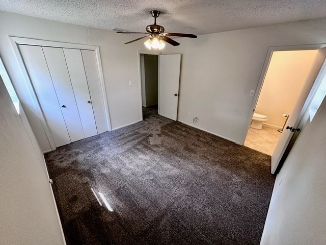 unfurnished bedroom with a closet, carpet flooring, ensuite bathroom, a textured ceiling, and ceiling fan