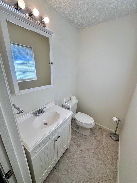 bathroom featuring vanity, a textured ceiling, toilet, and tile patterned flooring