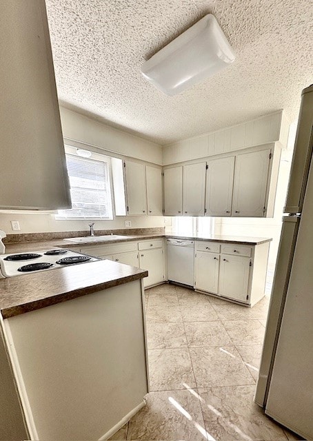 kitchen with a textured ceiling, sink, and white appliances