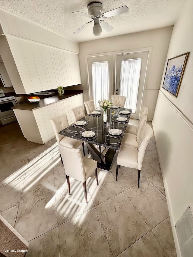 dining area with ceiling fan and a textured ceiling