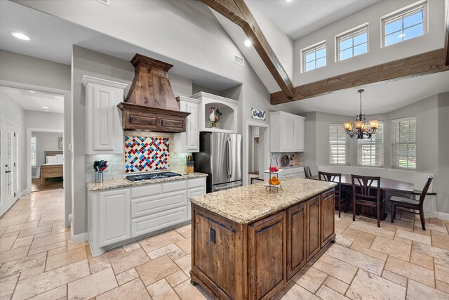 kitchen with a kitchen island, stainless steel appliances, white cabinets, and light stone counters