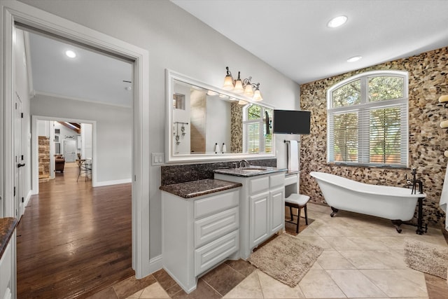 bathroom featuring a bathtub, hardwood / wood-style flooring, crown molding, and vanity