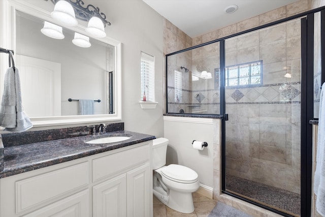 bathroom featuring toilet, tile patterned flooring, vanity, and a shower with shower door